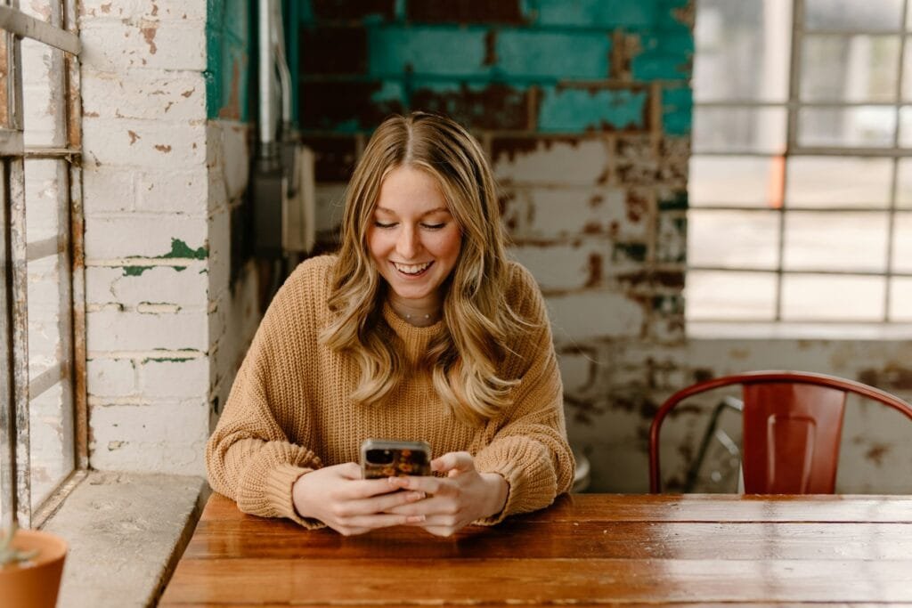 Woman smiling at her smartphone at a table