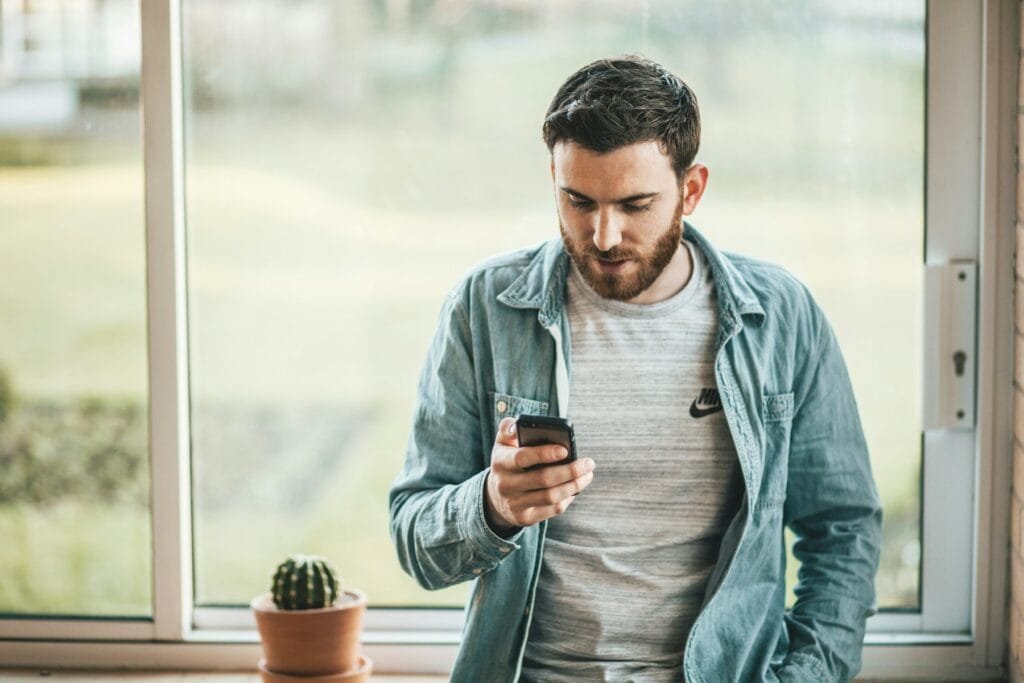 Man checking his smartphone by a window